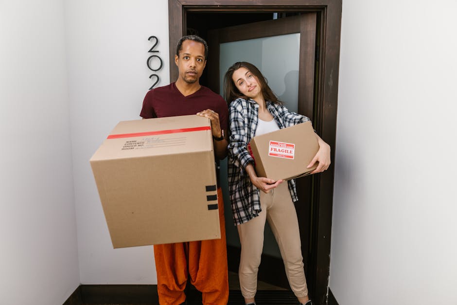 Close-up image of three light brown cardboard boxes placed on a wooden floor indoors, used for home relocation or packing during a house removal. The largest box on top is marked with the word 'STUFF'