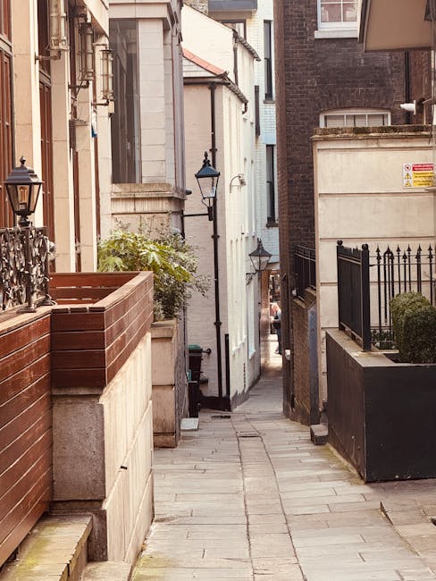 The image shows a city street scene in Pimlico, with a large, multi-storey brick building featuring white window frames and a rooftop terrace, situated adjacent to the sidewalk. In the foreground, the