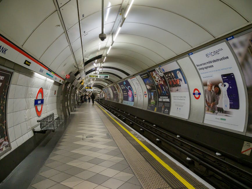 A deserted underground train station platform at night, illuminated by overhead lighting, with train tracks running along the length of the platform. The platform surface is made of concrete with tact
